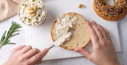 female-hands-spreading-cashew-cheese-on-a-bagel-2021-12-17-00-58-57-utc
