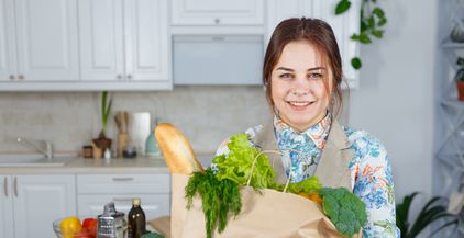 smiling-woman-in-the-kitchen-with-a-bag-of-groceri-2021-08-26-17-11-02-utc