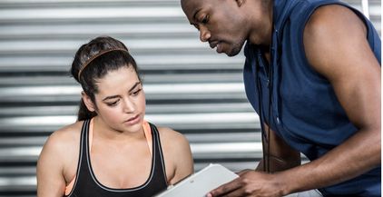 athletic-trainer-explaining-workout-plan-to-woman-2021-08-28-16-43-13-utc