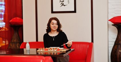 a-young-beautiful-girl-eating-sushi-on-traditional-2022-02-05-00-09-20-utc
