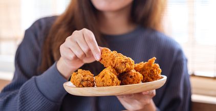 a-woman-holding-and-eating-fried-chicken-in-the-ki-2021-10-21-03-28-31-utc