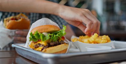 woman-eat-burger-in-fast-food-restaurant-2021-08-29-12-20-06-utc