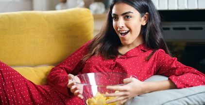 persian-woman-at-home-watching-tv-eating-chips-pot-2021-08-27-09-55-30-utc