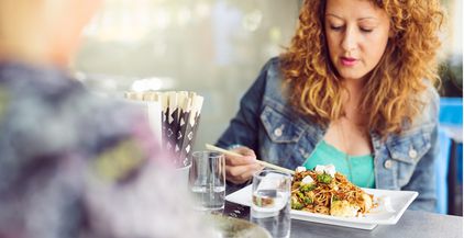 woman-eating-pasta-while-sitting-at-table-with-fri-2021-08-28-23-57-32-utc