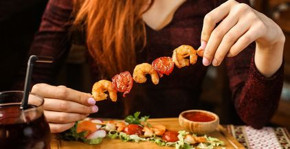 side-view-woman-eating-shrimp-on-a-skewer-with-veg-2021-08-31-16-11-54-utc