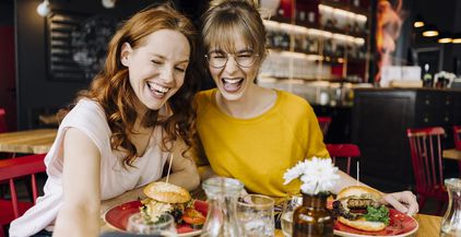 two-happy-female-friends-having-burger-and-taking-2022-03-08-01-25-05-utc