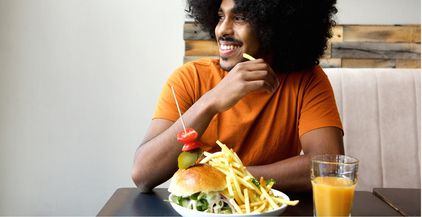 smiling-man-with-hamburger-and-fries-at-restaurant-2021-08-26-23-05-16-utc